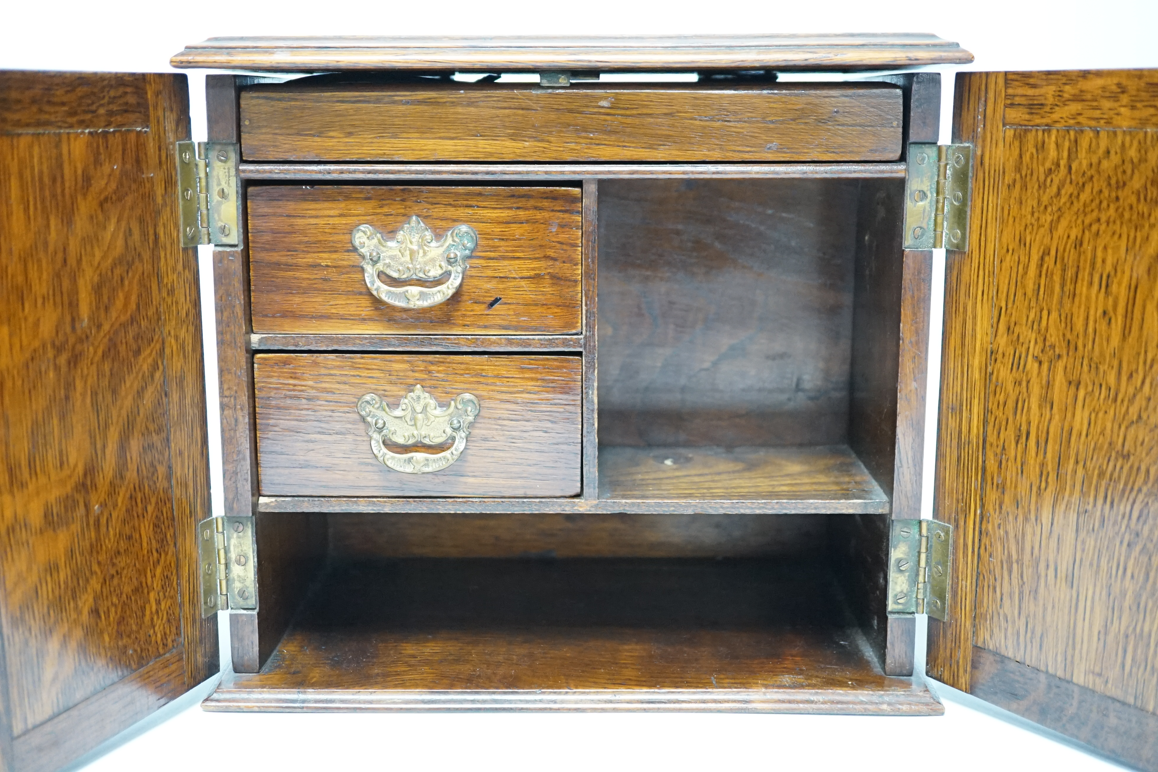 A carved oak smoker's compendium and accessories including cased cheroot holders, 25cm high